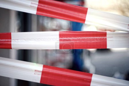 Zone fermée avec du ruban de barricade rouge et blanc vif. Image horizontale avec mise au point sélective.