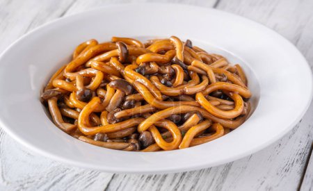 Portion of udon noodles with brown beach mushrooms