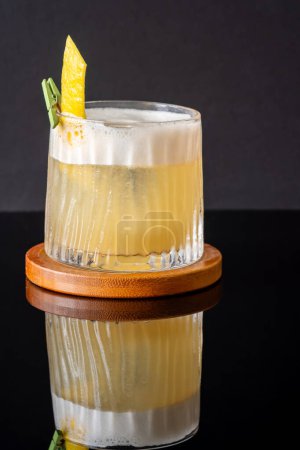 Glass of Whiskey sour cocktail garnished with lemon zest