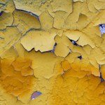The peeled paint is bright yellow, textured and attractive looks on the old wall in Kyiv on the territory of the art gallery of modern art Lavra.
