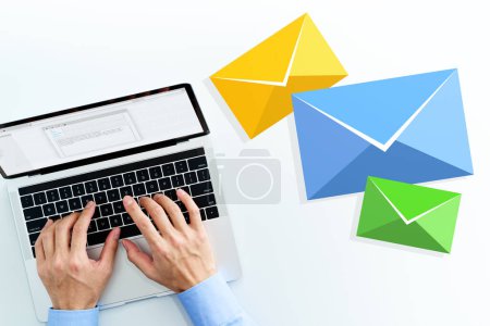 Photo for Business man writing email on white table. Top view of using laptop. Three email icons. - Royalty Free Image