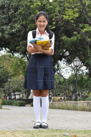 Foto de Estudiante bastante minoritaria y vestida de uniforme con libros de pie - Imagen libre de derechos