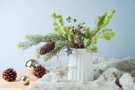 Foto de Decoración de mesa de Navidad con ramas de pino en jarrón y adornos sobre fondo brillante - Imagen libre de derechos