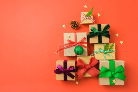 Foto de Cajas de regalo de Navidad con cintas de colores sobre fondo rojo en forma de árbol de Navidad. Envoltura de vacaciones y concepto de embalaje. Arriba. Puesta plana - Imagen libre de derechos