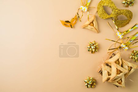 Jewish holiday Purim background with golden carnival mask and hamantaschen cookies. Top view, flat lay
