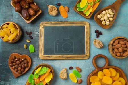 Foto de Dried dates, fruits and nuts with chalkboard on rustic background. Top view, flat lay. - Imagen libre de derechos