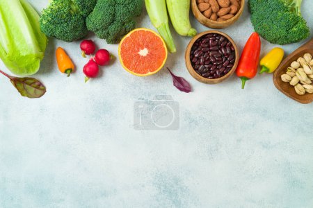 Foto de Vegetarian and vegan healthy lifestyle concept. Raw vegetables, nuts and fruits  over rustic background. Top view, flat lay - Imagen libre de derechos