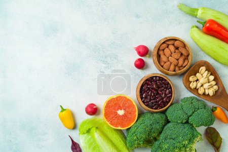 Foto de Vegetarian and vegan healthy lifestyle concept. Raw vegetables, nuts and fruits over rustic background. Top view, flat lay - Imagen libre de derechos