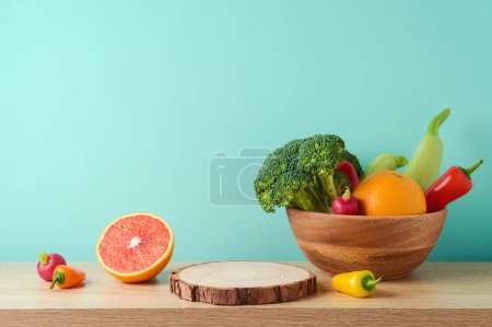 Empty wooden log with vegetables and fruits on table over blue wall  background. Vegetarian kitchen interior mock up for design and product display