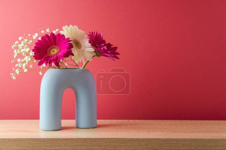 Foto de Spring flower bouquet in modern vase on wooden table over magenta background. Interior decoration - Imagen libre de derechos