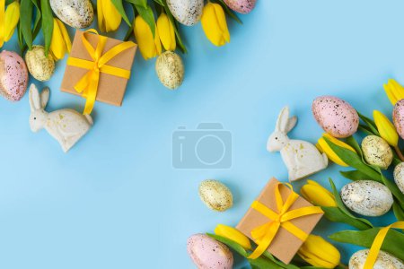 Foto de Easter holiday background with easter eggs, gift box and yellow  tulip flowers. Top view, flat lay - Imagen libre de derechos