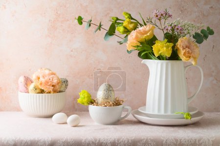 Foto de Celebración de vacaciones de Pascua con flores ramo y huevos de Pascua decoración en la mesa sobre fondo de pared de piedra - Imagen libre de derechos