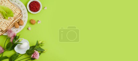 Photo for Jewish holiday Passover concept with matzah, seder plate and spring flowers on green background. Top view, flat lay - Royalty Free Image