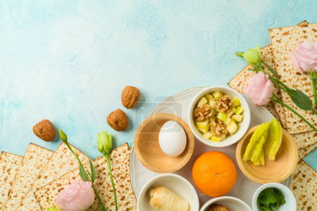 Photo for Modern Passover seder plate with matzah, spring flowers  and orange for LGBTQ equality on blue  background. Top view, flat lay - Royalty Free Image