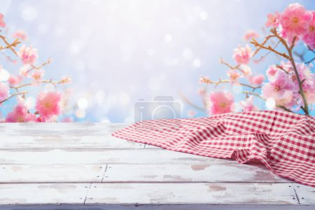 Téléchargez les photos : Table en bois vide avec nappe sur fond de fleurs de cerisier. Modèle de printemps et de Pâques pour la conception et l'affichage des produits - en image libre de droit