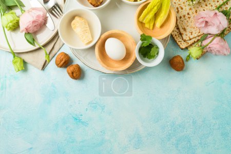 Photo for Jewish holiday Passover festive table setting with matzah, seder plate and spring flowers on blue  background. Top view, flat lay - Royalty Free Image