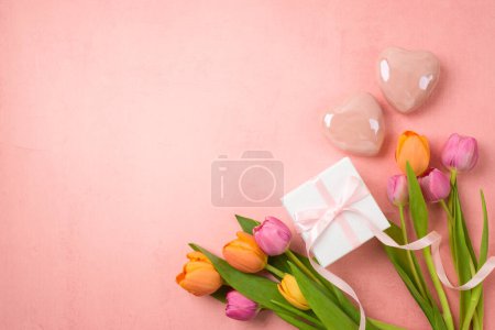 Foto de Concepto del día de la madre feliz con flores de tulipán, forma de corazón y caja de regalo sobre fondo rosa. Vista superior, plano - Imagen libre de derechos