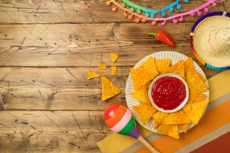 Foto de Concepto de fiesta mexicana Cinco de Mayo con nacho chips, maracas y sombrero sobre fondo de mesa de madera. Vista superior, plano - Imagen libre de derechos