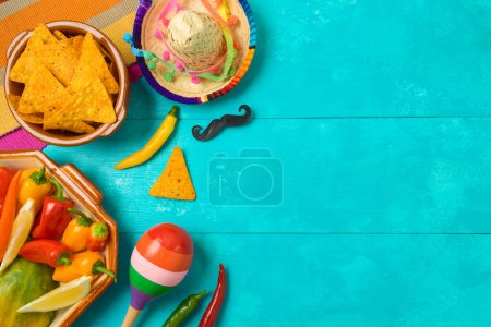 Foto de Tortillas de Nacho, pimientos, maracas y sombrero sombrero sobre fondo de madera azul. Fiesta mexicana Cinco de Mayo. Vista superior, plano - Imagen libre de derechos