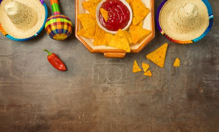 Foto de Mesa de fiesta mexicana con nacho chips, maracas y sombrero sombrero sobre fondo oscuro. Celebración del Cinco de Mayo. Vista superior, plano - Imagen libre de derechos