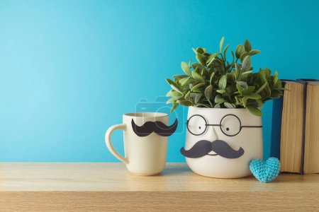 Foto de Concepto del día del padre feliz con linda planta divertida, taza de café y forma de corazón en la mesa de madera sobre fondo azul - Imagen libre de derechos