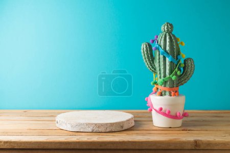 Photo for Empty wooden podium with  cactu decoration on wooden table over blue background. Cinco de Mayo Mexican holiday celebration - Royalty Free Image