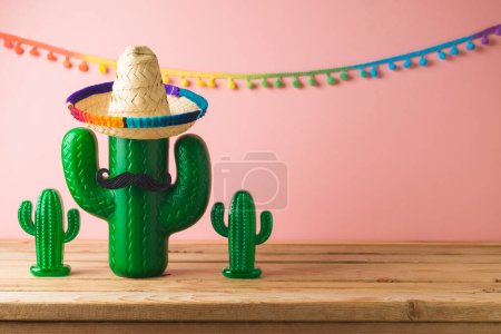 Foto de Concepto de fiesta mexicana con cactus y sombrero sombrero sobre mesa de madera sobre fondo rosa. Celebración del Cinco de Mayo - Imagen libre de derechos