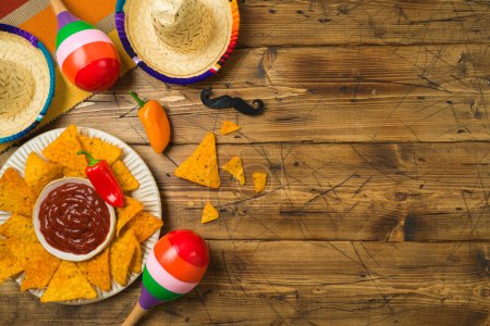 Photo for Cinco de Mayo Mexican holiday party concept with Nacho chips and sombrero hat on wooden background. Top view from above - Royalty Free Image