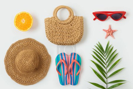 Téléchargez les photos : Des objets de vacances d'été. Sac de mode ; chapeau de plage, tongs et feuille de palmier sur fond blanc. Vue de dessus - en image libre de droit