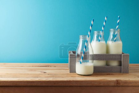 Foto de Judío concepto Shavuot vacaciones con botellas de leche en caja en la mesa de madera sobre fondo azul - Imagen libre de derechos