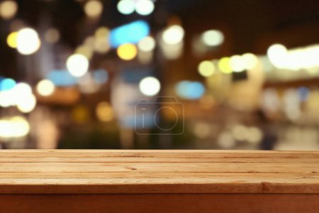 Foto de Mesa de madera vacía sobre fondo borroso abstracto de luces de noche bokeh. Mock up para el diseño y la visualización del producto. - Imagen libre de derechos