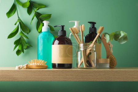 Photo for Natural cosmetics bottles with labels and bamboo toothbrush for mock up packaging design on wooden shelf over green leaves background - Royalty Free Image