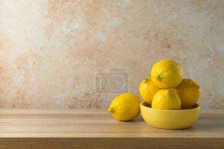 Foto de Limones en tazón amarillo sobre mesa moderna de madera. Simulación de la cocina para el diseño y la exhibición del producto - Imagen libre de derechos