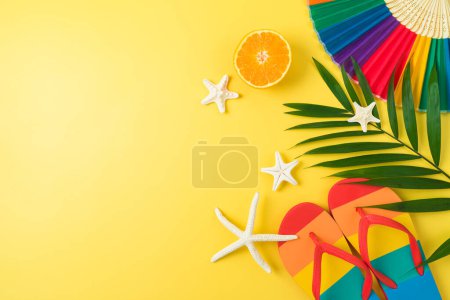 Téléchargez les photos : LGBTQ pride month beach party concept with rainbow flip flops palm leaf and paper fan on yellow background. Vue de dessus, plan plat - en image libre de droit