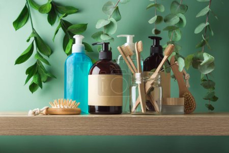 Téléchargez les photos : Flacons de cosmétiques naturels avec étiquettes et brosse à dents en bambou pour maquiller le design d'emballage sur étagère en bois sur fond de feuilles vertes - en image libre de droit