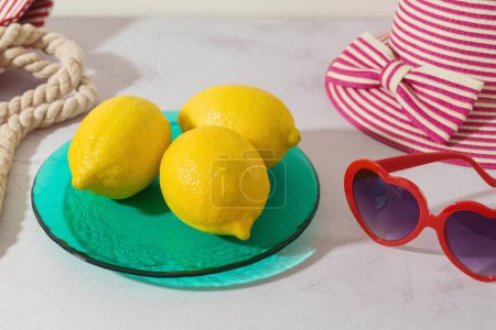 Téléchargez les photos : Été moderne fond créatif avec des citrons sur plaque colorée et accessoires de plage - en image libre de droit