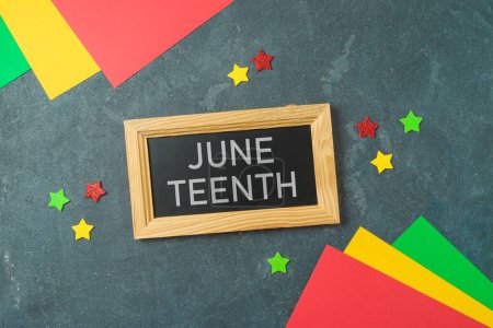 Juneteenth freedom day background with colorful paper, blackboard sign and stars. Top view, flat lay