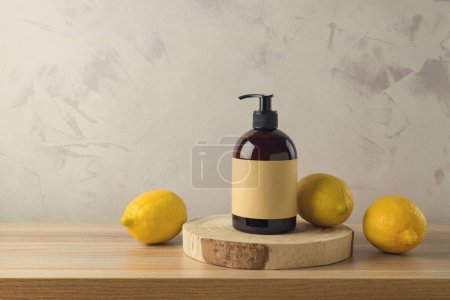 Foto de Botella de champú o gel de ducha con extracto de limón sobre mesa de madera. Simular el fondo de diseño de envases - Imagen libre de derechos