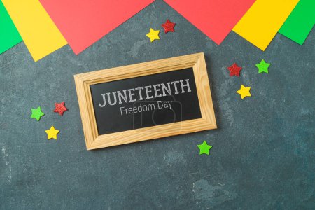 Photo for Juneteenth holiday day background with colorful paper, chalkboard sign and stars. Top view, flat lay - Royalty Free Image