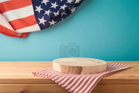 Téléchargez les photos : Grumes de podium en bois vides avec nappe sur la table sur fond drapeau des États-Unis. Modèle de fête nationale américaine pour le design et l'affichage des produits - en image libre de droit