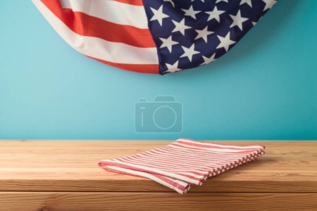 Téléchargez les photos : Table en bois vide avec nappe sur fond drapeau des États-Unis. Modèle de fête nationale américaine pour le design et l'affichage des produits - en image libre de droit
