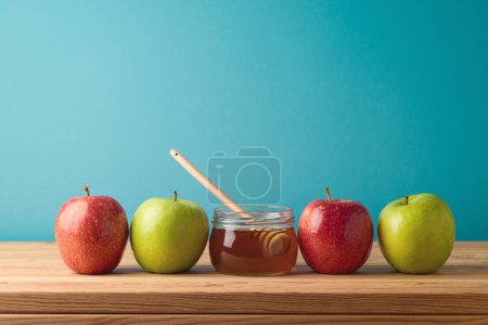 Photo for Honey jar and apples on wooden table over blue background. Jewish holiday Rosh Hashanah concept - Royalty Free Image