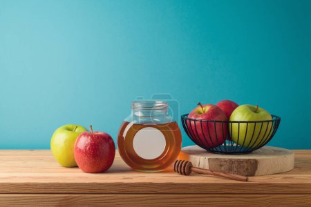 Foto de Tarro de miel y manzanas sobre mesa de madera sobre fondo azul. Fiesta judía Rosh Hashaná concepto - Imagen libre de derechos
