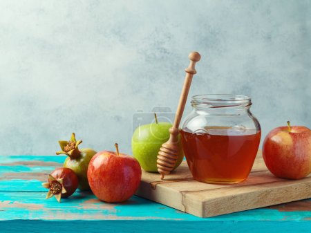 Téléchargez les photos : Pot de miel, pommes rouges et grenade sur table bleue en bois. Contexte des vacances juives Rosh Hashanah - en image libre de droit