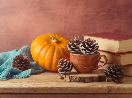 Téléchargez les photos : Concept d'automne avec cône de pin dans une tasse à café, citrouille et livres sur table en bois. Carte de vœux Thanksgiving - en image libre de droit