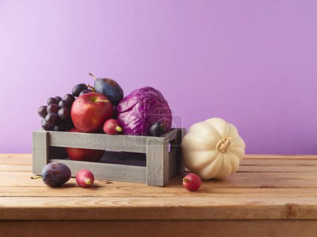 Téléchargez les photos : Concept de récolte d'automne. Citrouille, pomme, raisin et légumes en boîte en bois sur la table sur fond violet - en image libre de droit