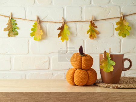 Photo for Coffee cup and pumpkin decoration on wooden shelf over brick wall background with autumn leaf garland. Thanksgiving holiday greeting card - Royalty Free Image