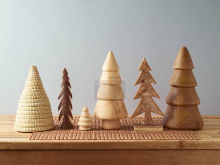 Foto de Moderno concepto de decoración navideña sostenible. Árboles de Navidad de madera en la mesa sobre fondo de pared gris. - Imagen libre de derechos