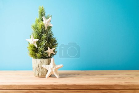 Foto de Árbol de Navidad creativo con decoración de estrellas de mar sobre mesa de madera sobre fondo azul - Imagen libre de derechos