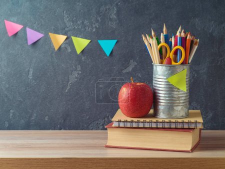 Foto de Volver a la escuela fondo con lápices, libro y manzana en la mesa de madera sobre fondo pizarra - Imagen libre de derechos